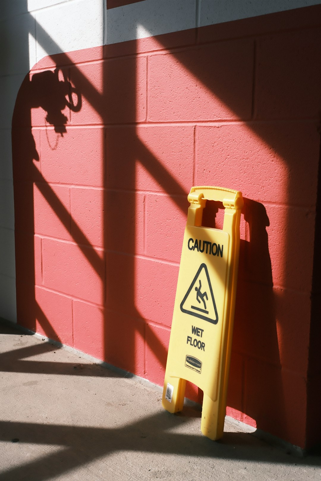 yellow-caution-sign-for-wet-floor-on-pink-wall-knilrgkc4hq